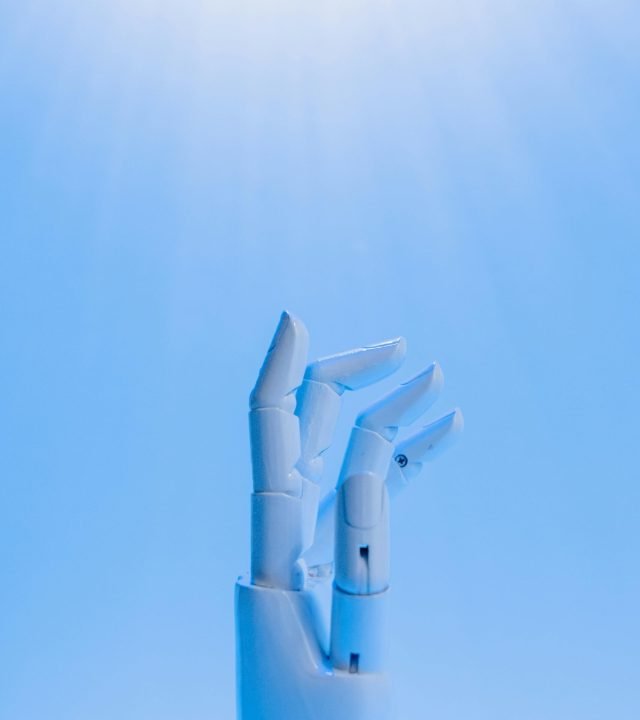 A robotic hand reaching upward against a blue sky, symbolizing technology's future.